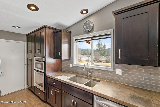 kitchen with dark brown cabinetry, recessed lighting, stainless steel appliances, a sink, and decorative backsplash