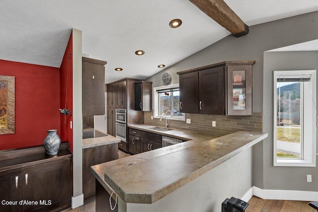 kitchen with vaulted ceiling with beams, light wood-style flooring, backsplash, a sink, and dark brown cabinets