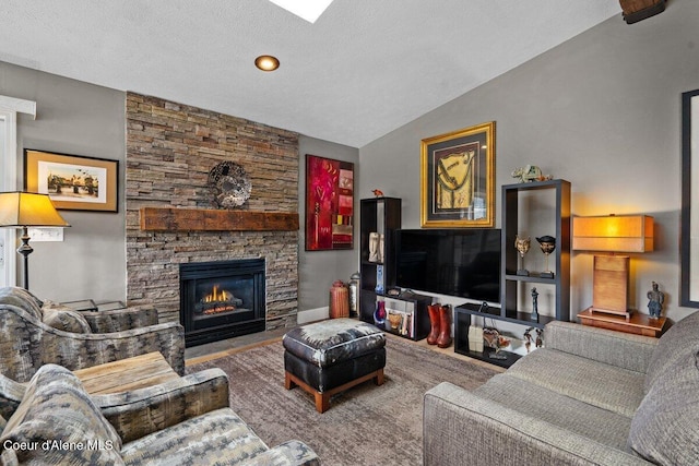 living room with vaulted ceiling, a stone fireplace, and a textured ceiling