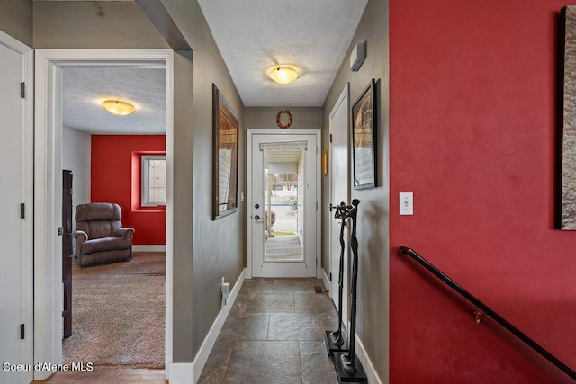 entryway featuring stone tile flooring, a healthy amount of sunlight, baseboards, and a textured ceiling