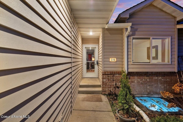 view of exterior entry featuring brick siding