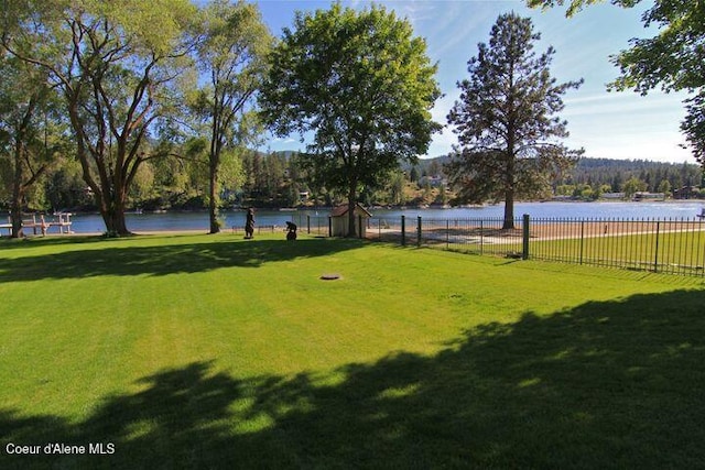 view of property's community featuring a yard, a water view, and fence