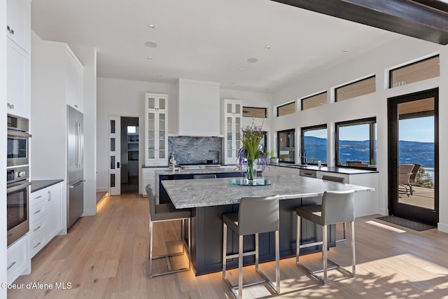2766 S Helen Dr, Coeur Dalene, ID 83814 - kitchen featuring backsplash, appliances with stainless steel finishes, glass insert cabinets, a mountain view, and an island with sink