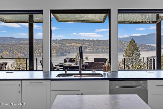 2766 S Helen Dr, Coeur Dalene, ID 83814 - kitchen featuring a forest view, stainless steel dishwasher, white cabinets, and a sink