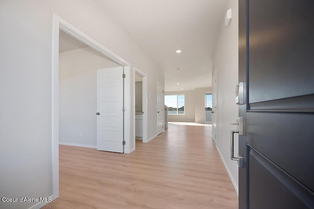 hallway with baseboards, light wood finished floors, and recessed lighting