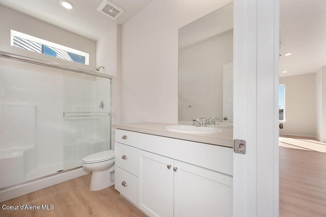 bathroom with visible vents, toilet, wood finished floors, vanity, and a shower stall