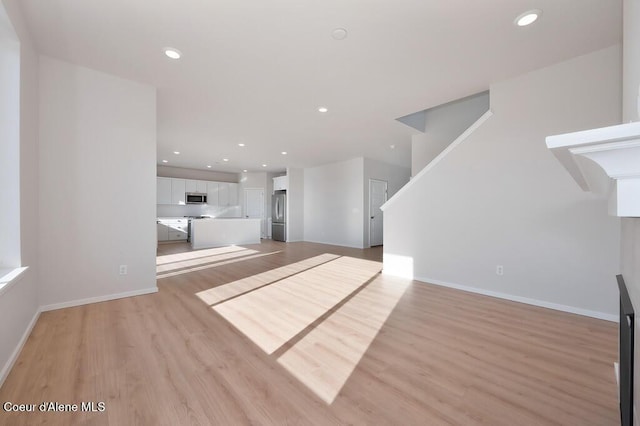 unfurnished living room featuring baseboards, recessed lighting, and light wood-style floors