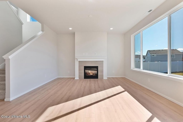 unfurnished living room with a fireplace, recessed lighting, stairway, wood finished floors, and baseboards