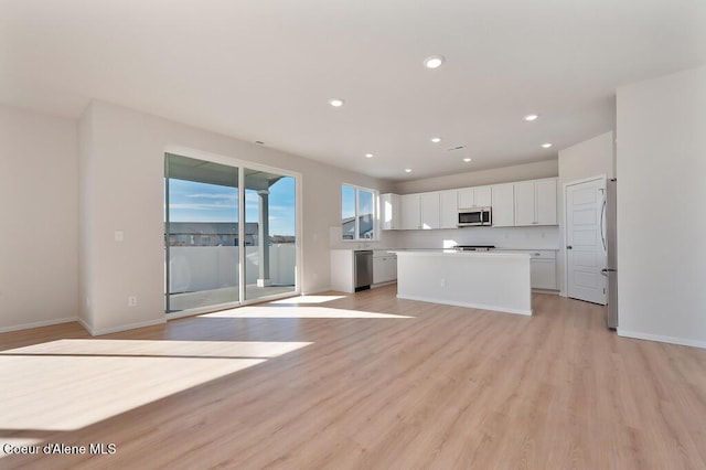 kitchen with baseboards, white cabinets, light wood-style floors, appliances with stainless steel finishes, and a center island