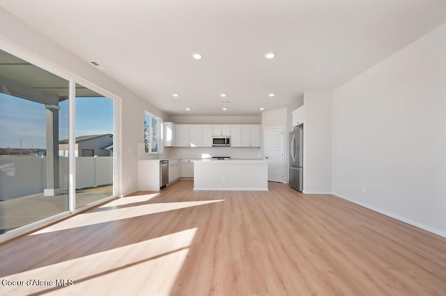 interior space featuring light wood finished floors, baseboards, a sink, and recessed lighting