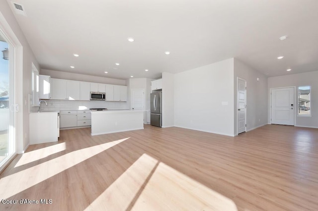 kitchen with a center island, stainless steel appliances, light wood-style flooring, open floor plan, and white cabinets