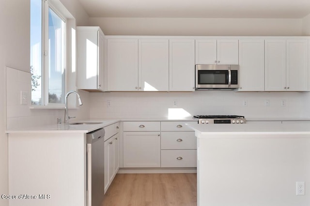 kitchen featuring stainless steel appliances, white cabinetry, a sink, and tasteful backsplash