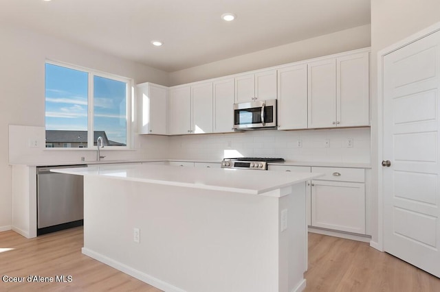 kitchen featuring a sink, stainless steel appliances, a kitchen island, and white cabinetry