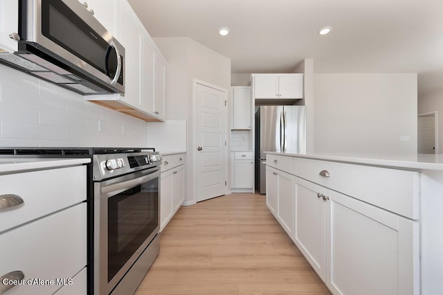 kitchen featuring stainless steel appliances, white cabinetry, light countertops, backsplash, and light wood finished floors