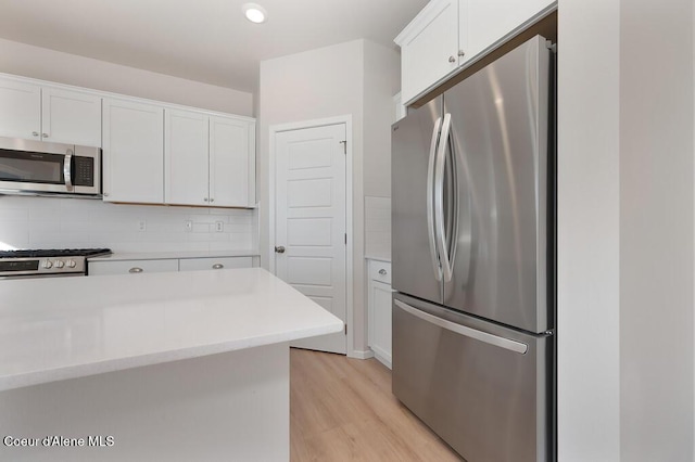 kitchen with stainless steel appliances, tasteful backsplash, light countertops, and white cabinets