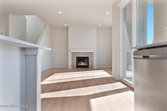 unfurnished living room featuring a fireplace, baseboards, wood finished floors, and recessed lighting