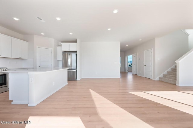 kitchen with appliances with stainless steel finishes, white cabinetry, light wood-style flooring, and recessed lighting