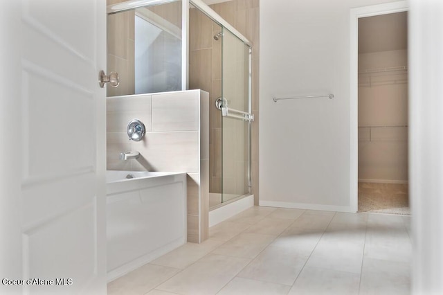 full bathroom with a stall shower, tile patterned flooring, a spacious closet, and baseboards