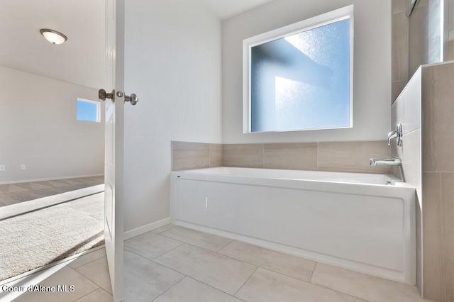 bathroom featuring tile patterned flooring, baseboards, and a bath