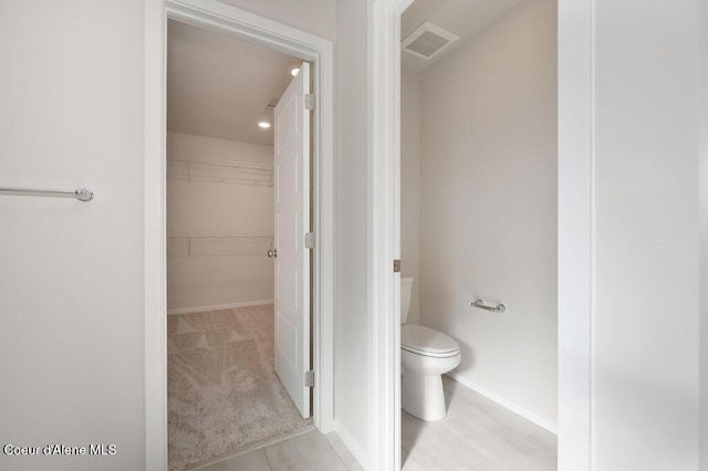 bathroom featuring baseboards, visible vents, a spacious closet, and toilet