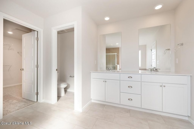 bathroom with a walk in closet, a sink, toilet, and double vanity