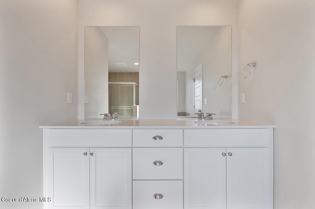 full bath with a sink, a shower stall, and double vanity