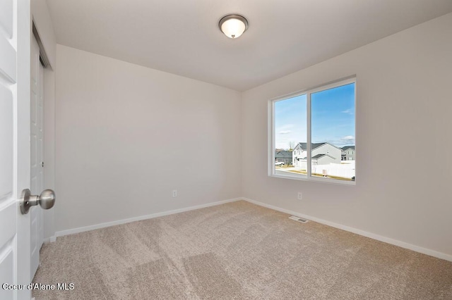 empty room featuring carpet floors, baseboards, and visible vents