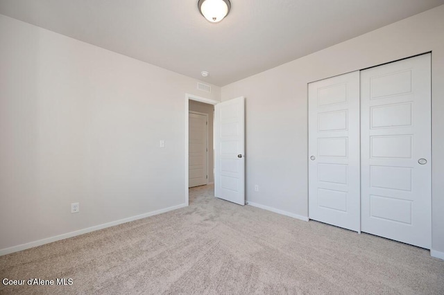 unfurnished bedroom featuring carpet floors, a closet, visible vents, and baseboards