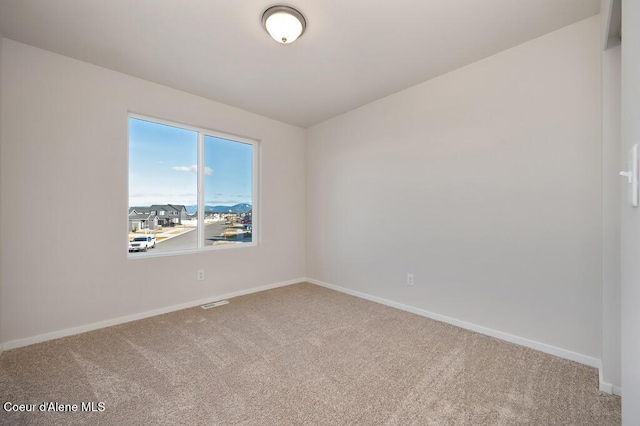 spare room featuring carpet floors and baseboards