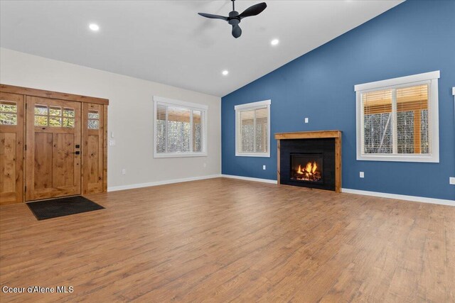 unfurnished living room with ceiling fan, high vaulted ceiling, recessed lighting, wood finished floors, and a lit fireplace