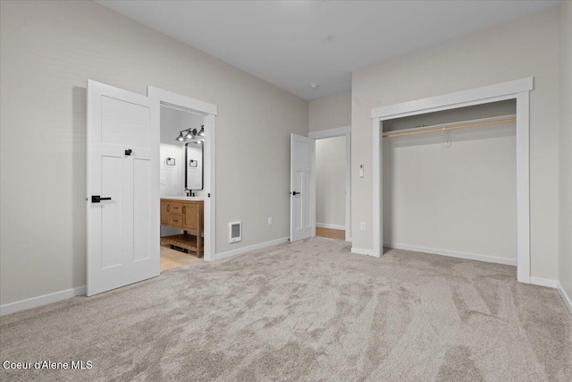 unfurnished bedroom featuring a closet, baseboards, carpet flooring, and ensuite bath
