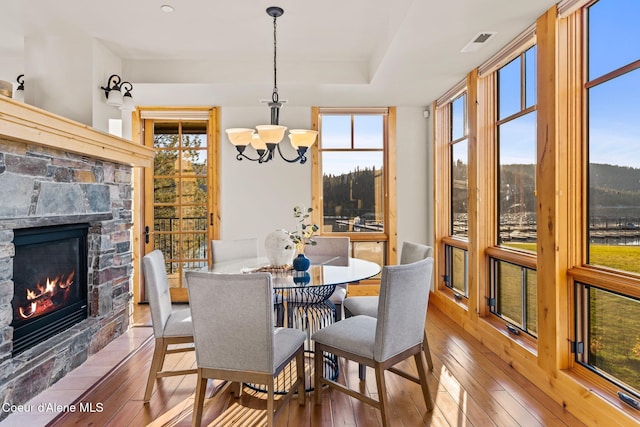 dining area with a healthy amount of sunlight, hardwood / wood-style floors, and a stone fireplace