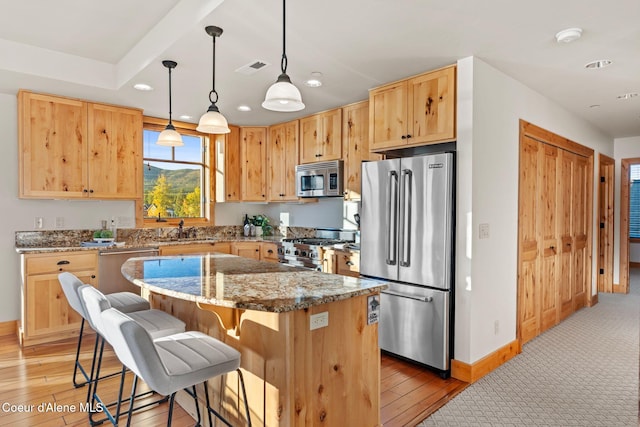 kitchen with a breakfast bar, light wood-style flooring, stainless steel appliances, and a center island