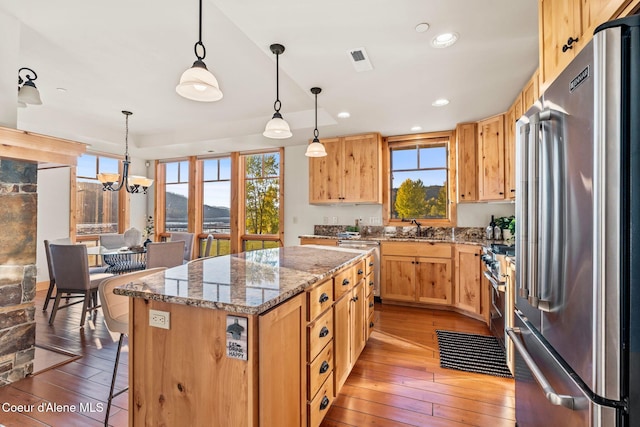 kitchen featuring stainless steel appliances, a kitchen island, a sink, and light wood-style flooring