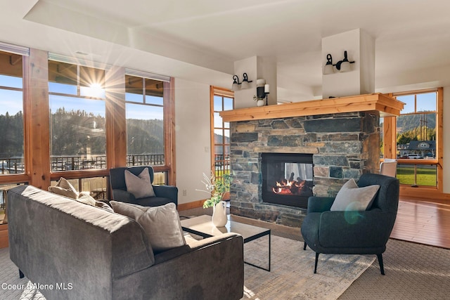 living area featuring a stone fireplace and a healthy amount of sunlight