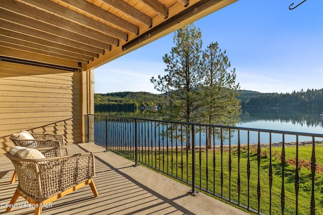 balcony featuring a water view and a view of trees