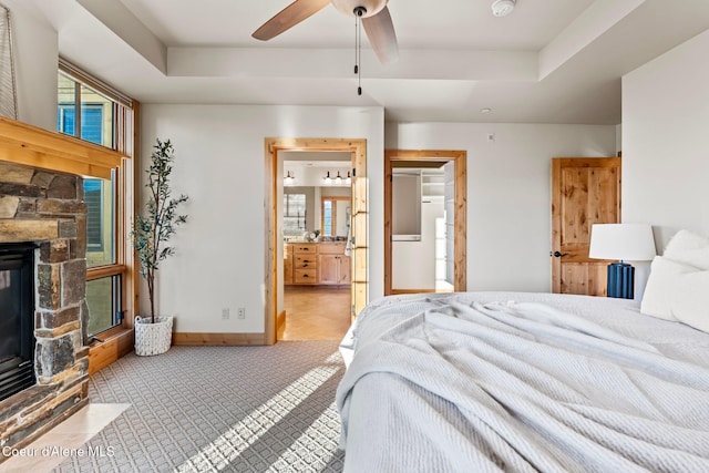 bedroom with a raised ceiling, a fireplace, ensuite bath, and baseboards