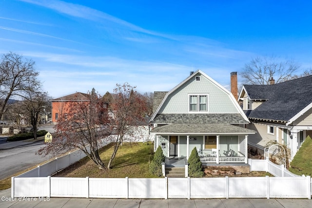 view of front of home featuring roof with shingles, a porch, a fenced front yard, and a gambrel roof