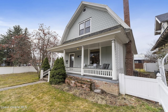 view of front of house with a porch, a chimney, a front yard, and fence