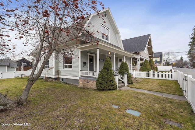 view of front of house featuring a shingled roof, covered porch, a gambrel roof, a fenced backyard, and a front lawn