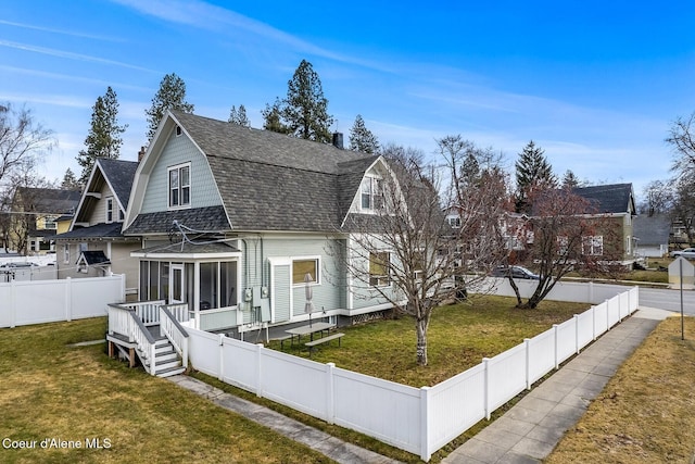 view of front of house with a sunroom, roof with shingles, a front lawn, and a gambrel roof