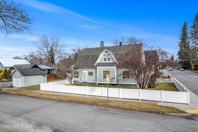 colonial inspired home with an outbuilding, roof with shingles, and a fenced front yard