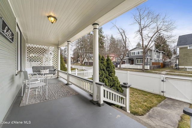 view of patio with covered porch, a gate, a residential view, and fence