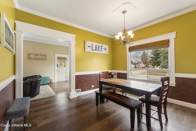 dining space featuring wood-type flooring, wainscoting, visible vents, and an inviting chandelier