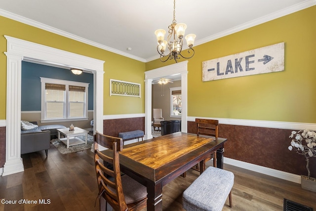 dining room featuring wood finished floors, visible vents, wainscoting, ornate columns, and crown molding