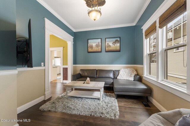 living area featuring wood finished floors, visible vents, baseboards, ornamental molding, and decorative columns