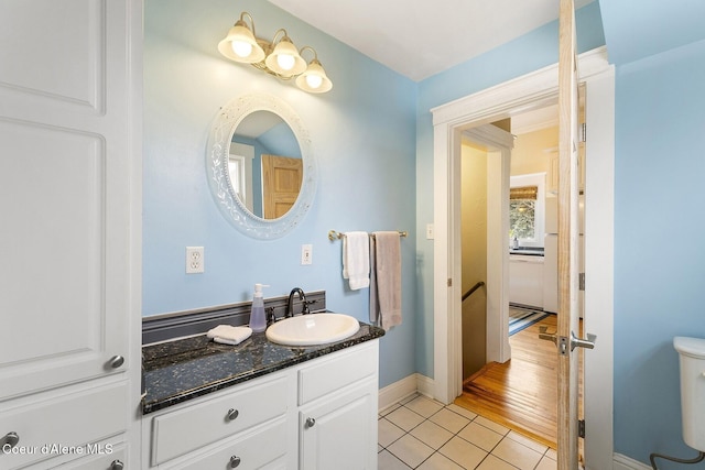 half bath featuring tile patterned flooring, baseboards, vanity, and toilet