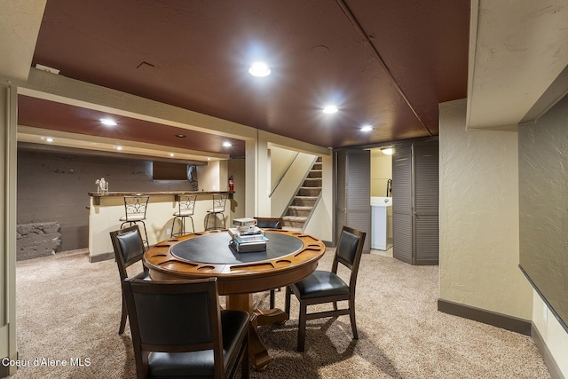 dining room featuring stairs, a textured wall, washer / clothes dryer, and carpet flooring