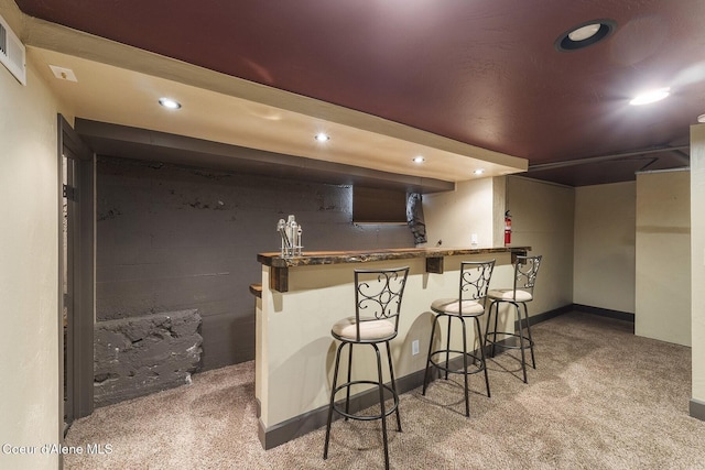 kitchen with a kitchen bar, carpet flooring, visible vents, and recessed lighting