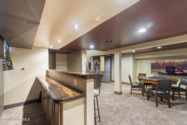 bar featuring recessed lighting, baseboards, light carpet, and a bar